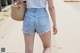 a woman wearing a white top and blue denim shorts