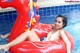 A woman in a bikini laying on an inflatable swan in a pool.