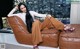 A woman sitting on a brown couch in a living room.