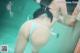 A woman in a white bikini standing in a pool.