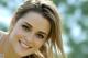 A beautiful young woman with long brown hair smiling.