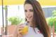 A woman holding a glass of orange juice with a straw.