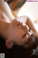 A woman laying on top of a bed next to a window.