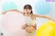 A little girl sitting on the floor with a bunch of balloons.