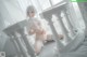 A woman in a white lingerie sitting on a bed.