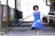 A woman in a blue dress is walking down the street.