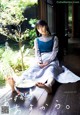 A woman sitting on a wooden floor next to a bowl of water.