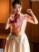 A woman in a pink and white hanbok is posing for a picture.