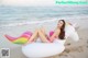 A woman in a pink bikini sitting on an inflatable unicorn on the beach.