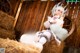 A woman sitting on top of a pile of hay next to a teddy bear.