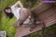 A woman in black pantyhose is sitting on a wooden bench.