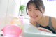 A woman laying in a bathtub with a bunch of balloons.