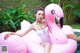 A woman in a white bathing suit sitting on a pink flamingo float.