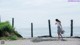 A woman walking down a road next to the ocean.